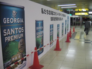 ＪＲ札幌駅にて。「私たち北海道コカ・コーラボトリングは、知床自然保護を応援します」北海道限定　世界遺産〔知床〕デザイン缶の看板（左）